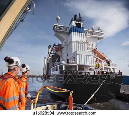 Workers on tug boat overlooking ship View Large Photo Image Picture - Workers on tug boat overlooking ship. Fotosearch