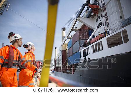 Stock Image - Workers on tug boat overlooking ship. Fotosearch