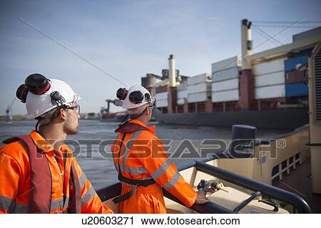 Workers on tug boat overlooking ship View Large Photo Image Stock Image - Workers on tug boat overlooking ship. Fotosearch