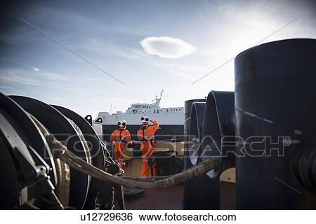 Workers on tug boat overlooking ship View Large Photo Image Stock Photograph - Workers on tug boat overlooking ship. Fotosearch