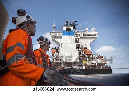 Workers on tug boat pulling in rope View Large Photo Image Picture - Workers on tug boat pulling in rope. Fotosearch