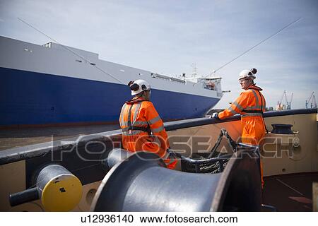 Stock Image - Workers on tug boat talking. Fotosearch