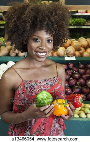 African American woman holding bell peppers at supermarket View Large Photo Image Picture - African American woman holding bell peppers at supermarket. Fotosearch