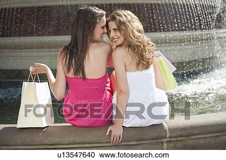 Back view of two young female friends communicating while sitting by water fountain View Large Photo Image Stock Image - Back view of two young female friends communicating while sitting by water fountain. Fotosearch