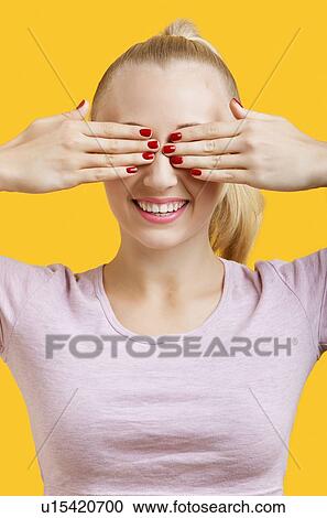 Beautiful young woman covering eyes over yellow background View Large Photo Image Stock Image - Beautiful young woman covering eyes over yellow background. Fotosearch