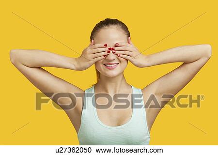 Beautiful young woman covering eyes over yellow background View Large Photo Image Stock Image - Beautiful young woman covering eyes over yellow background. Fotosearch