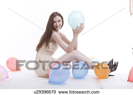 Beautiful young woman in dress on floor with balloons against white background View Large Photo Image Stock Photo - Beautiful young woman in dress on floor with balloons against white background. Fotosearch