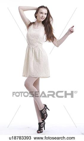 Stock Image - Beautiful young woman in dress with hand in her hair looking away against white background. Fotosearch