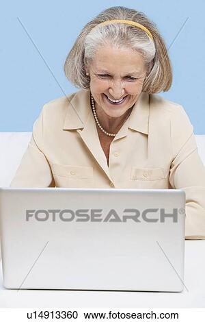 Stock Image - Cheerful senior woman using laptop for video calling. Fotosearch