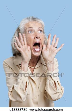 Frightened senior woman screaming against blue background View Large Photo Image Stock Photo - Frightened senior woman screaming against blue background. Fotosearch