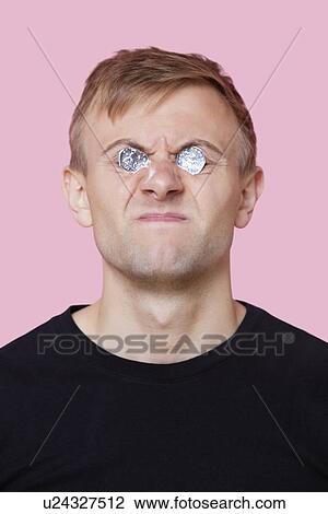 Funny young man covering eyes with coins over pink background View Large Photo Image Stock Image - Funny young man covering eyes with coins over pink background. Fotosearch