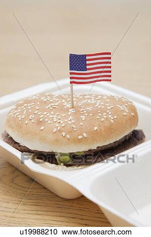 Stock Image - Grilled hamburger with American flag decoration on wooden surface. Fotosearch