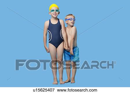 Stock Photo - Happy young boy and girl in swimwear holding hands over blue background. Fotosearch