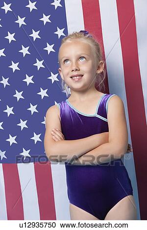 Happy young female gymnast with arms crossed standing in front of American flag View Large Photo Image Stock Image - Happy young female gymnast with arms crossed standing in front of American flag. Fotosearch