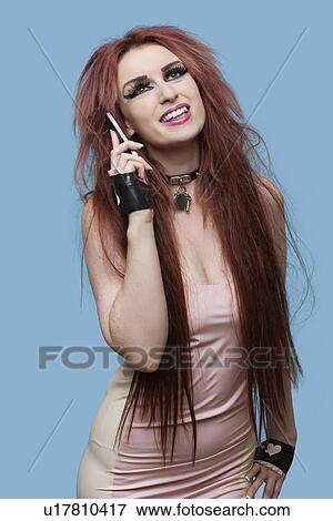 Happy young funky woman using cell phone over blue background View Large Photo Image Stock Photo - Happy young funky woman using cell phone over blue background. Fotosearch