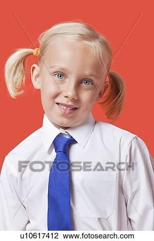 Stock Image - Portrait of a cute young girl in school uniform over blue background. Fotosearch