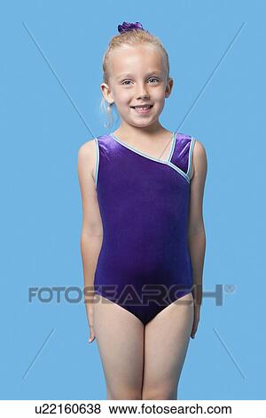 Portrait of a happy female gymnast standing over blue background View Large Photo Image Stock Photo - Portrait of a happy female gymnast standing over blue background. Fotosearch