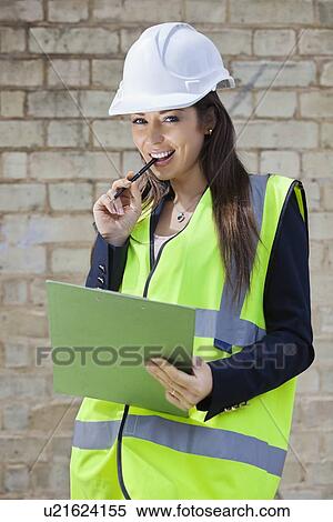 Portrait of a happy female supervisor with clipboard standing at construction site View Large Photo Image Stock Photography - Portrait of a happy female supervisor with clipboard standing at construction site. Fotosearch