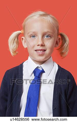 Stock Photograph - Portrait of a happy schoolgirl in uniform over orange background. Fotosearch