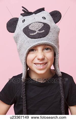Stock Photo - Portrait of a happy young boy wearing monkey cap over pink background. Fotosearch