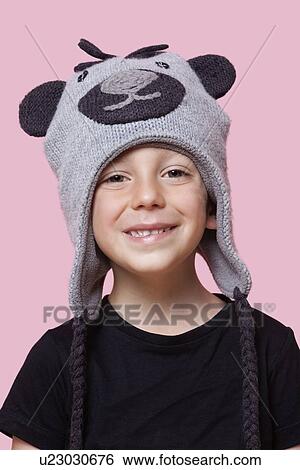 Stock Photograph - Portrait of a happy young boy wearing monkey cap over pink background. Fotosearch