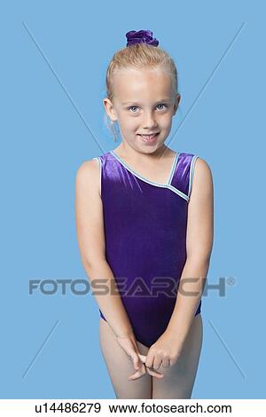 Portrait of a happy young female gymnast standing over blue background View Large Photo Image Stock Photo - Portrait of a happy young female gymnast standing over blue background. Fotosearch