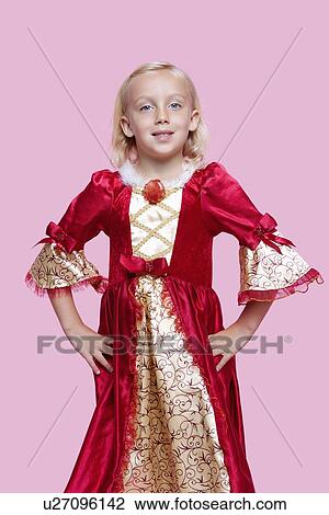 Stock Image - Portrait of a happy young girl dressed in princess costume over pink background. Fotosearch