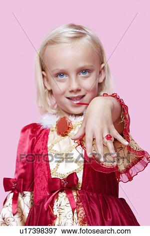 Portrait of a happy young girl dressed in princess costume displaying ring over pink background View Large Photo Image Stock Photo - Portrait of a happy young girl dressed in princess costume displaying ring over pink background. Fotosearch