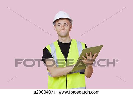 Portrait of a male construction worker with clipboard over pink background View Large Photo Image Stock Image - Portrait of a male construction worker with clipboard over pink background. Fotosearch