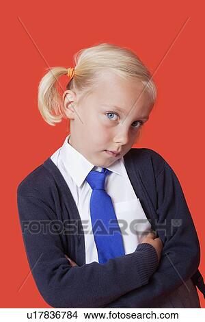 Portrait of a young schoolgirl with arms crossed over orange background View Large Photo Image Picture - Portrait of a young schoolgirl with arms crossed over orange background. Fotosearch