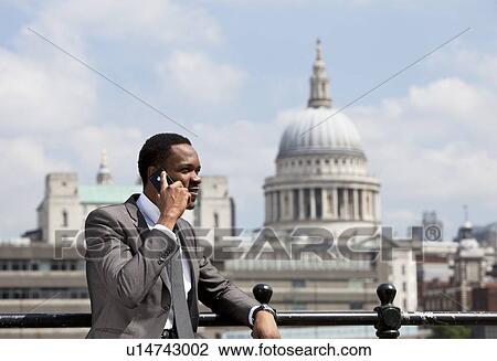 Stock Image - Portrait of African American businessman talking on Cell phone in London. Fotosearch