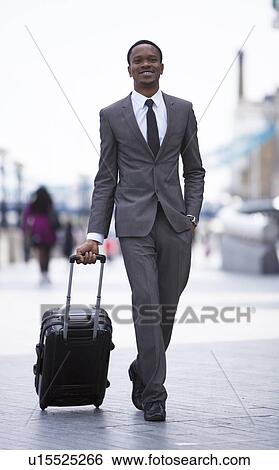 Portrait of African American businessman smiling and pulling suitcase View Large Photo Image Stock Photograph - Portrait of African American businessman smiling and pulling suitcase. Fotosearch