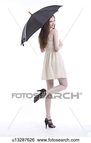 Stock Photograph - Portrait of beautiful young woman in dress with umbrella against white background. Fotosearch