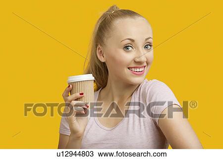 Portrait of beautiful young woman holding disposable cup over yellow background View Large Photo Image Stock Image - Portrait of beautiful young woman holding disposable cup over yellow background. Fotosearch