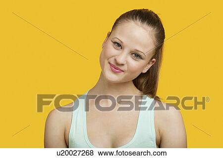 Stock Photo - Portrait of beautiful young woman smiling over yellow background. Fotosearch