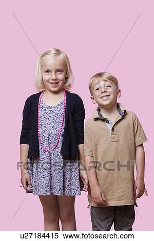 Stock Photography - Portrait of happy brother and sister standing over pink background. Fotosearch