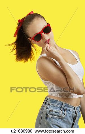 Portrait of playful young woman in sunglasses eating lollipop over yellow background View Large Photo Image Stock Image - Portrait of playful young woman in sunglasses eating lollipop over yellow background. Fotosearch