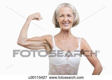 Stock Photo - Portrait of senior woman flexing muscles against white background. Fotosearch
