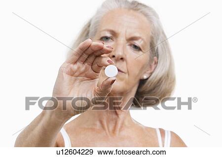 Portrait of senior woman holding a pill against white background View Large Photo Image Stock Photo - Portrait of senior woman holding a pill against white background. Fotosearch