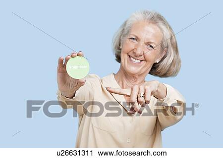 Portrait of senior woman holding volunteer badge against blue background View Large Photo Image Stock Image - Portrait of senior woman holding volunteer badge against blue background. Fotosearch