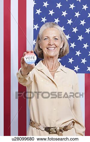 Portrait of senior woman holding election badge against American flag View Large Photo Image Stock Image - Portrait of senior woman holding election badge against American flag. Fotosearch