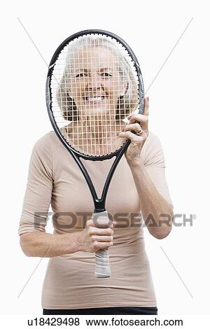 Portrait of senior woman holding tennis racket in front of her face against white background View Large Photo Image Stock Photo - Portrait of senior woman holding tennis racket in front of her face against white background. Fotosearch