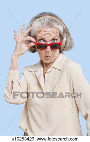 Portrait of senior woman wearing sunglasses against blue background View Large Photo Image Stock Photo - Portrait of senior woman wearing sunglasses against blue background. Fotosearch