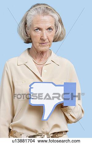 Portrait of senior woman with fake dislike button against blue background View Large Photo Image Picture - Portrait of senior woman with fake dislike button against blue background. Fotosearch