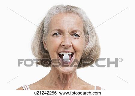 Portrait of senior woman with pill between her teeth against white background View Large Photo Image Stock Photograph - Portrait of senior woman with pill between her teeth against white background. Fotosearch