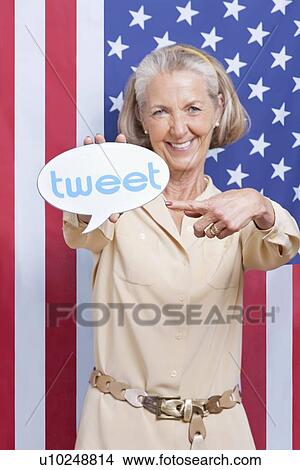 Picture - Portrait of senior woman with tweet bubble against American flag. Fotosearch