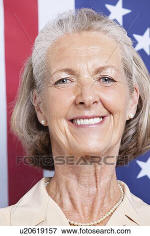 Stock Photo - Portrait of smiling senior woman against American flag. Fotosearch