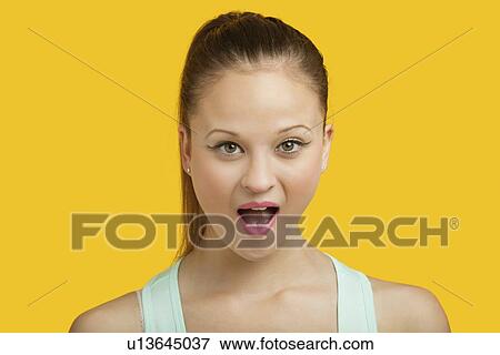 Portrait of surprised young woman with mouth open over yellow background View Large Photo Image Stock Photo - Portrait of surprised young woman with mouth open over yellow background. Fotosearch