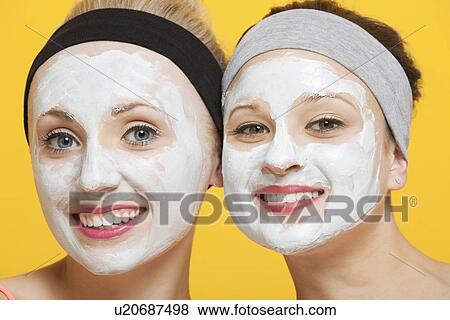 Portrait of two happy women with face pack on their faces over yellow background View Large Photo Image Stock Photo - Portrait of two happy women with face pack on their faces over yellow background. Fotosearch