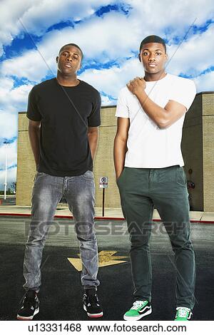 Portrait of two young men in casual wear standing on road View Large Photo Image Stock Photo - Portrait of two young men in casual wear standing on road. Fotosearch